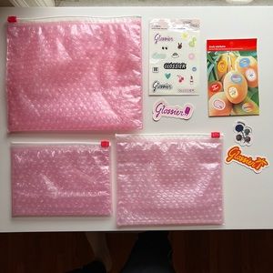 Glossier stickers and pouches